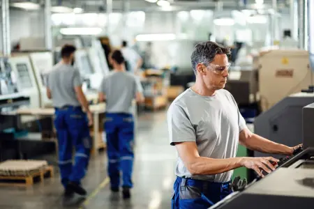 Ein mittlerer Angestellter bedient eine CNC-Maschine in einer industriellen Anlage.